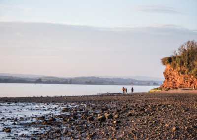 People walking across Exe estuary beach towards horizon